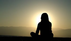 silhouette of teen in lotus position
