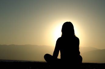silhouette of teen in lotus position