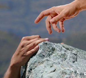 hands reaching over a rock