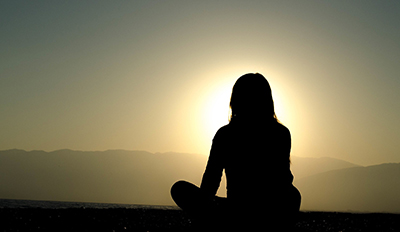 silhouette of woman sitting cross-legged