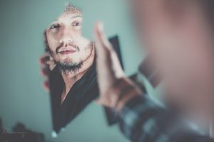 man reflected in broken mirror