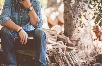 man holding book and pondering