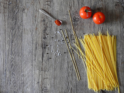 a handful of uncooked spaghetti and two small tomatoes on a table