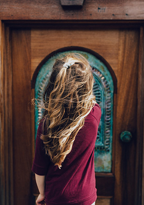 child standing outside of a closed door