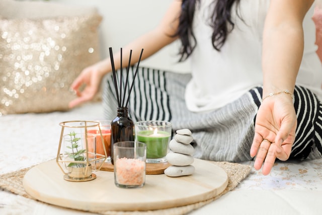 woman in "om" position with candles, incense, stones