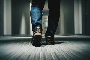 man walking down hallway toward door