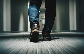 man walking down hallway toward door