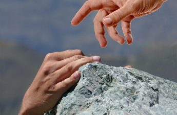 hands reaching over a rock