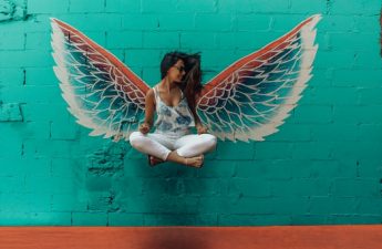 girl appearing to float in front of a pair of wings painted on a wall