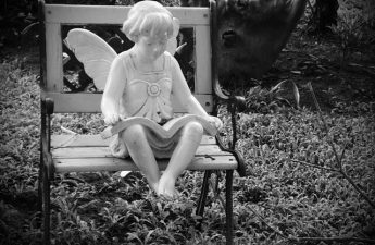 statue of angel reading Bible