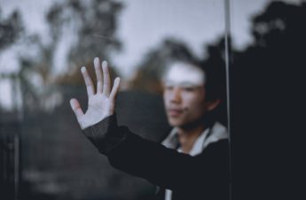 man behind window looking lonely