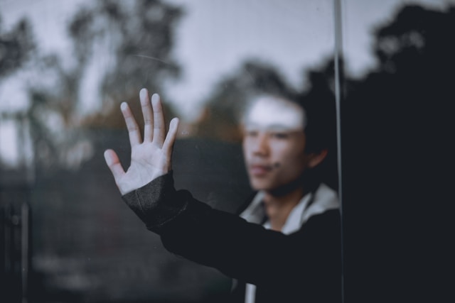 man behind window looking lonely