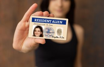 purposeful woman holding "resident alien" card