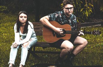 downcast youth, one holding a guitar