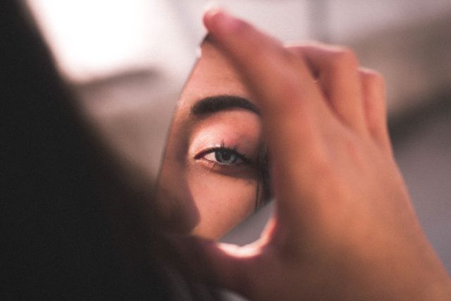 part of woman's face reflected in a broken mirror shard