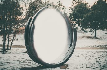 large glowing round mirror-like object in a natural landscape
