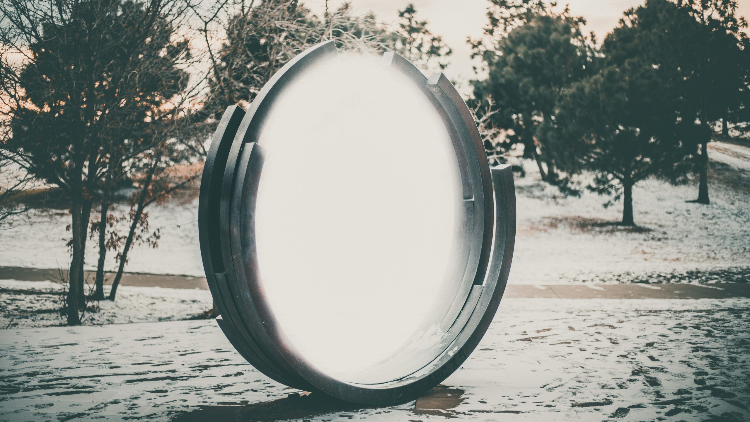 large glowing round mirror-like object in a natural landscape